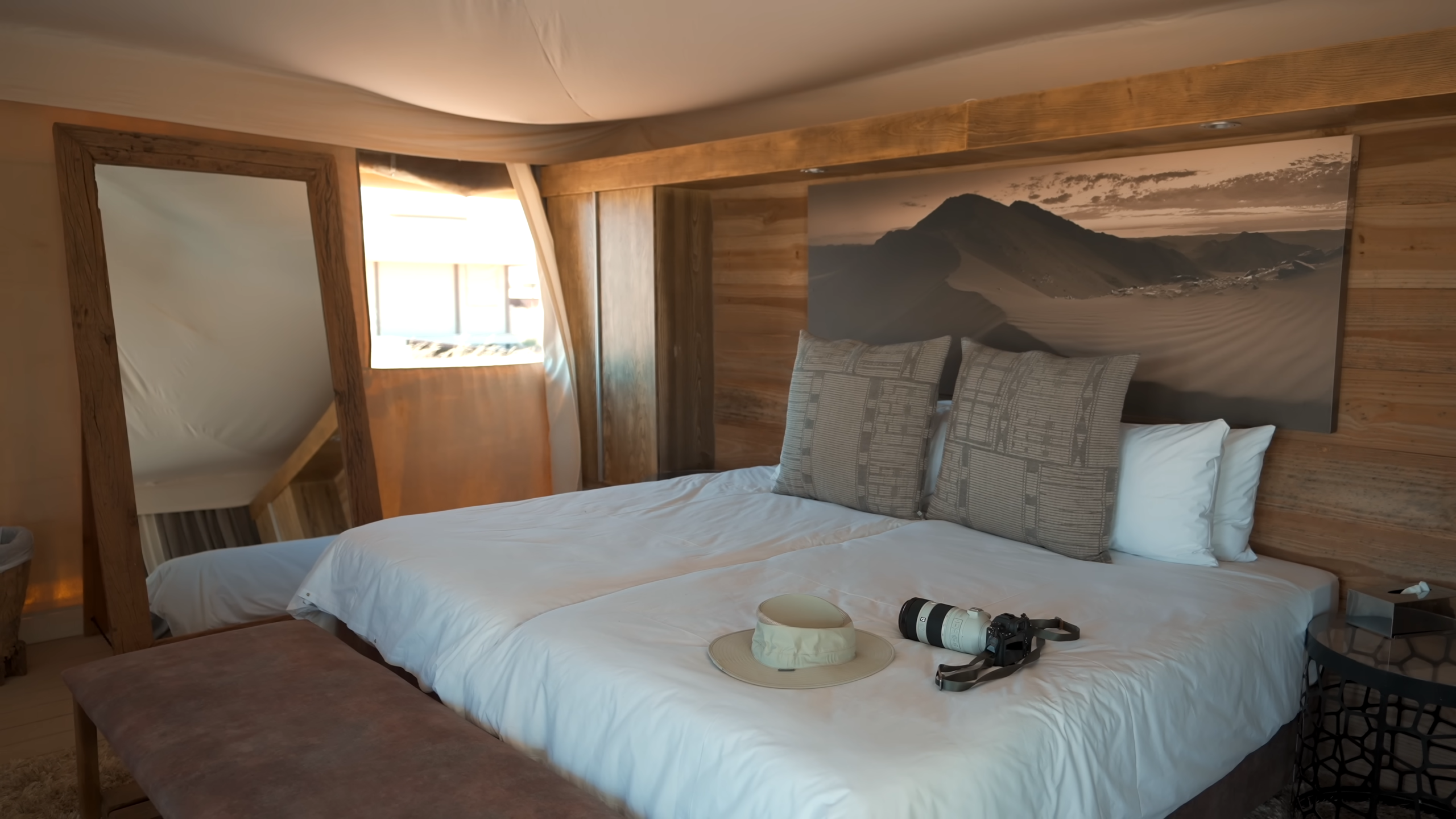 Elegant luxury bedroom interior in a Namibian desert lodge with soft natural light, wooden accents, and scenic views of the surrounding landscape