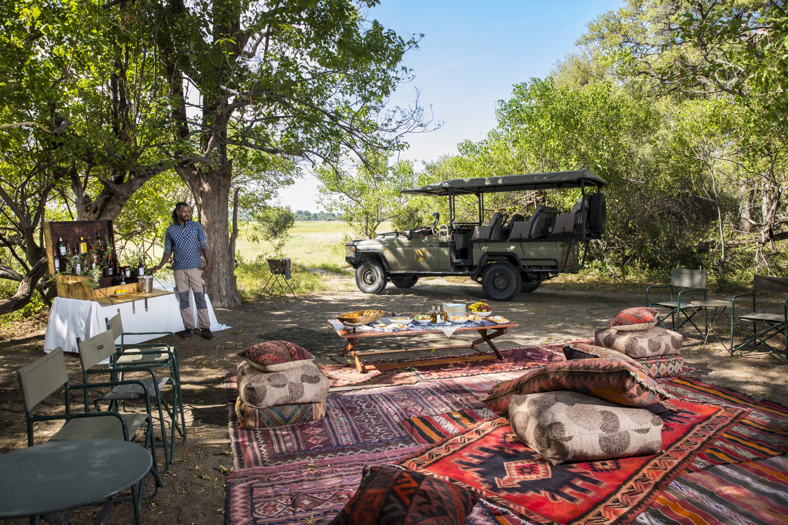 Outdoor brunch setup with safari vehicle, near the Khwai River in Botswana’s Okavango Delta.