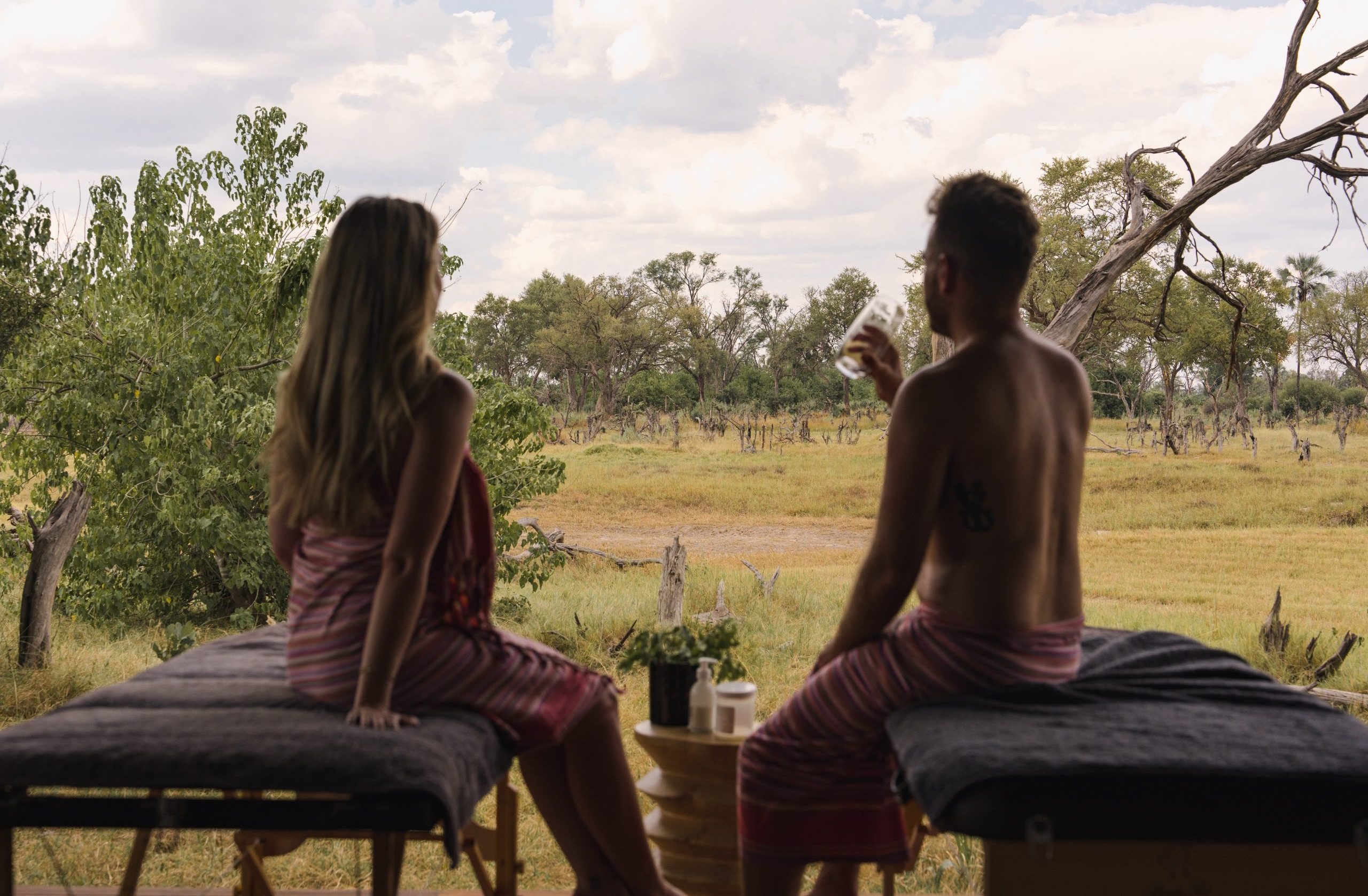 A honeymoon couple relaxes at Gomoti Plains Camp in the Okavango Delta, combining wilderness adventure with intimate luxury_Mtembezi African Safaris